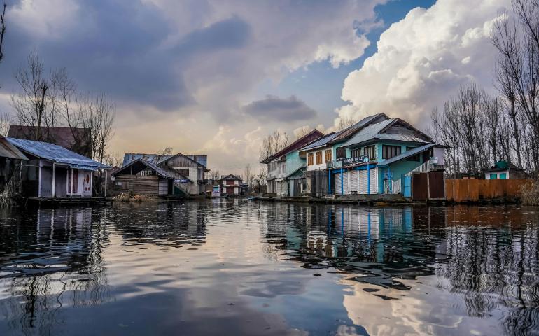 View of Traditional Houses by Dal Lake in Kashmir Under Dramatic Clouds