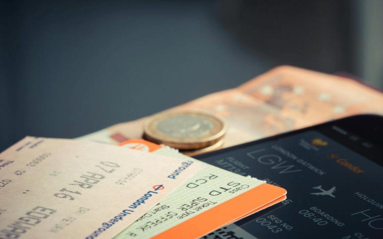 Airline Ticket with Euro Coins and Smartphone Displaying Flight Details