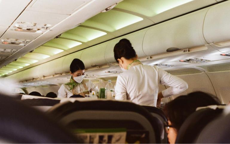 Flight Attendants in Masks Serving Passengers During a Flight