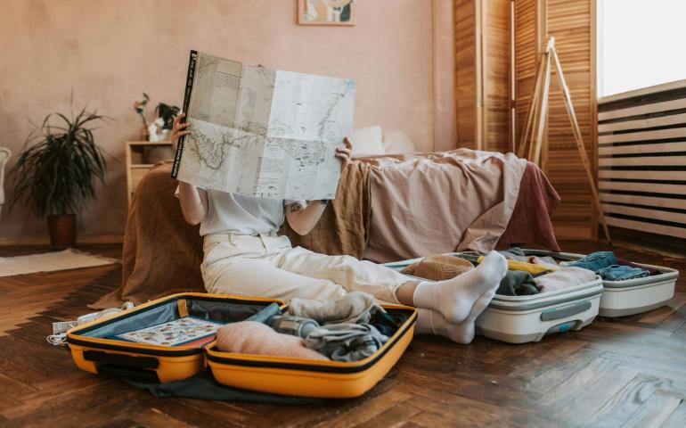 Person Packing Suitcases With a Map in a Cozy Bedroom, Preparing for a Journey.