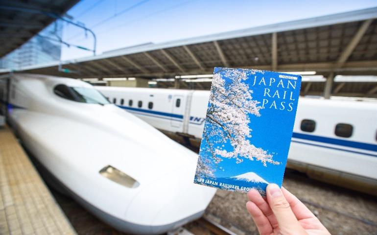 A traveller holding a JR Pass ticket in front of Shinkansen at Tokyo Station