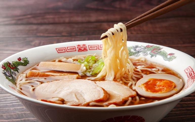 Soy sauce ramen noodles lifted with chopsticks.