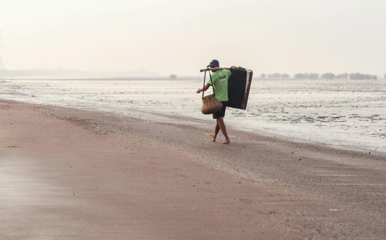 Fisherman walking in the Dumas Beach