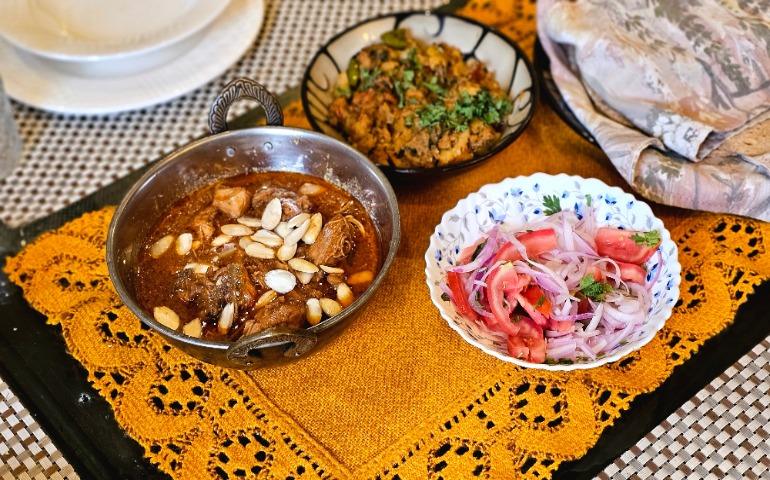 Delicious Indian Meal Featuring a Hearty Curry with Almonds and Fresh Salad on a Decorative Mat