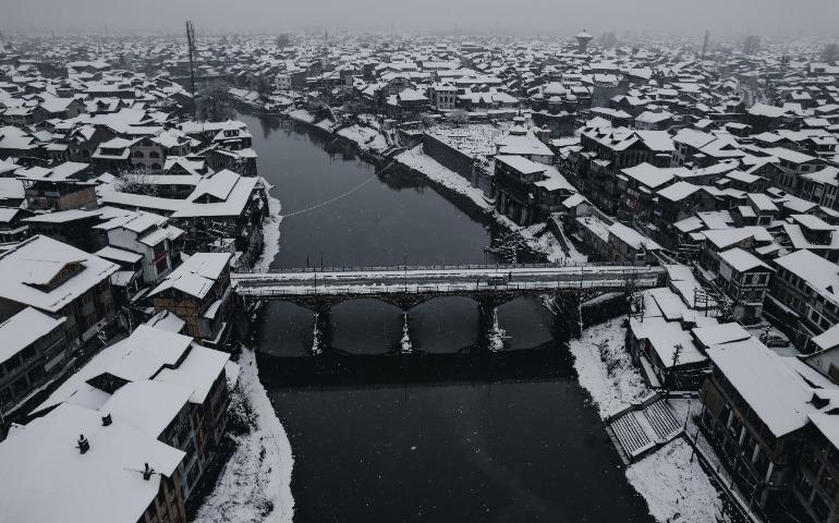 View of Srinagar's Snow-Covered Cityscape with a River and Bridge During Winter