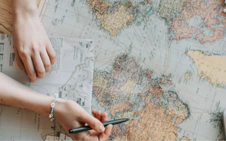 Person planning a journey with a world map