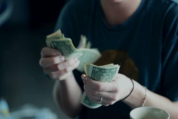 A twenty-four year old woman counting dollar bills.
