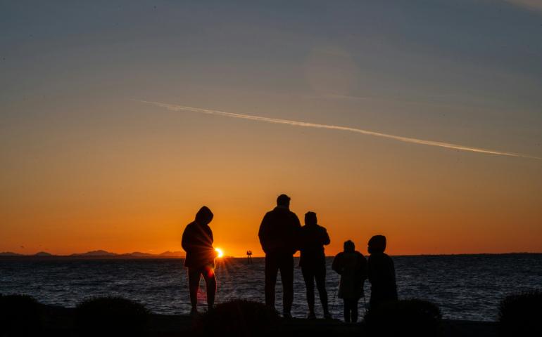 Silhouette of people standing on the seashore during sunset
