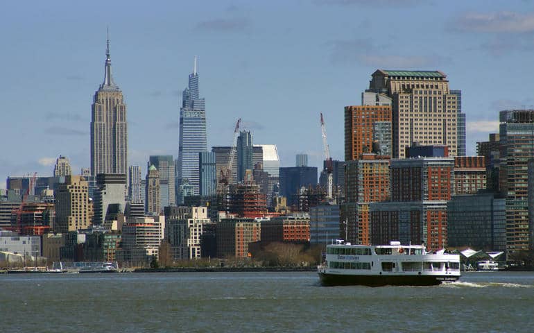 New York panorama view with the Empire State Building and a ferry in the front

