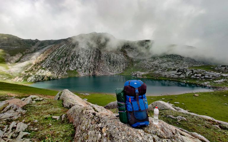 View of a Mountain Lake with a Blue Backpack - Perfect for Travel and Adventure Enthusiasts.