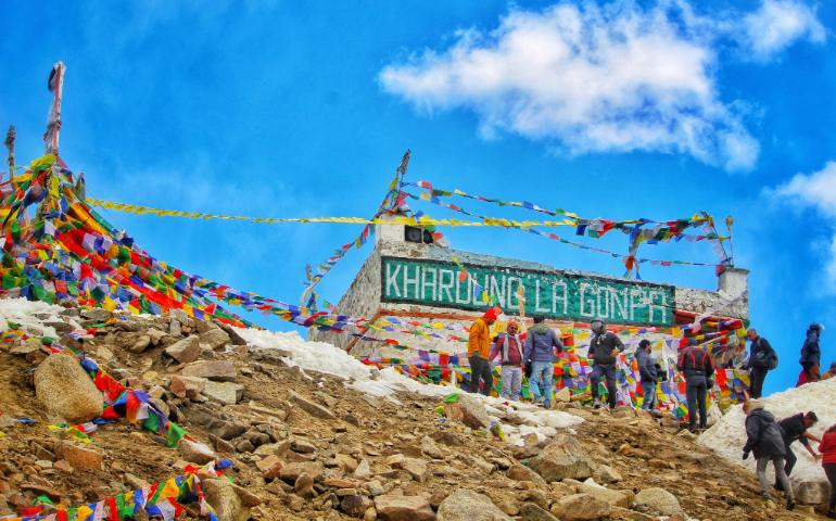 Khardung La Pass with people and prayer flags in Ladakh, India.