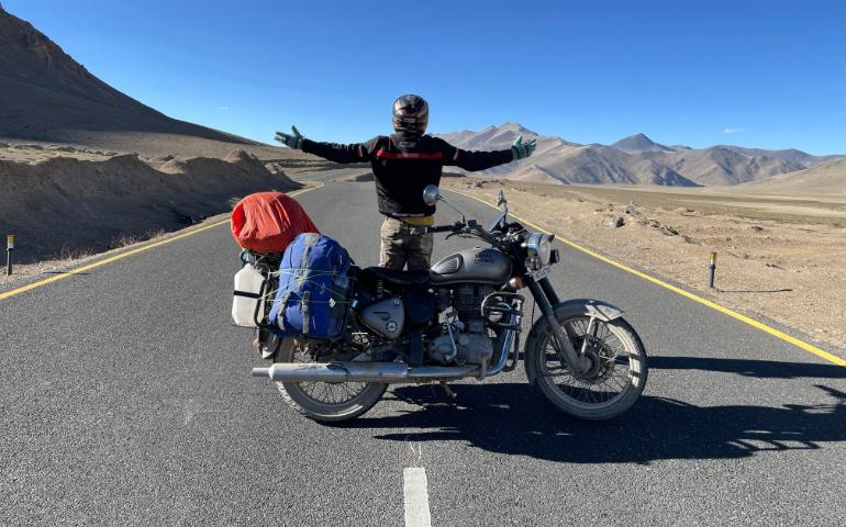 Motorcyclist stands on an empty road in Leh.
