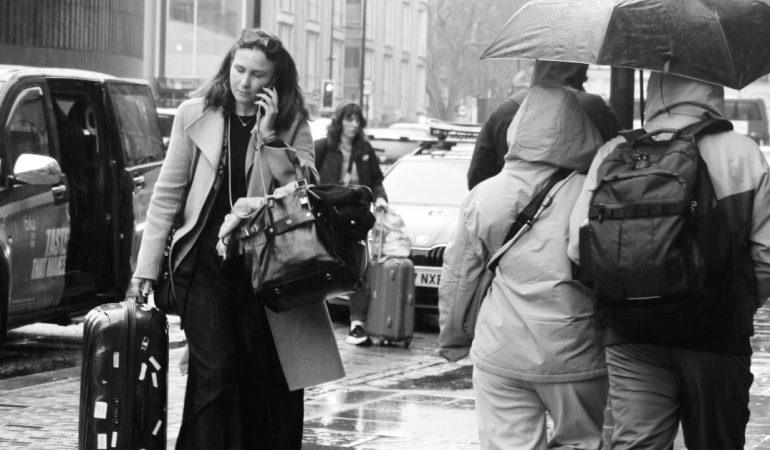 People travelling on a rainy street with luggage and umbrellas.
Image Credit: Jon Adams/Pexels