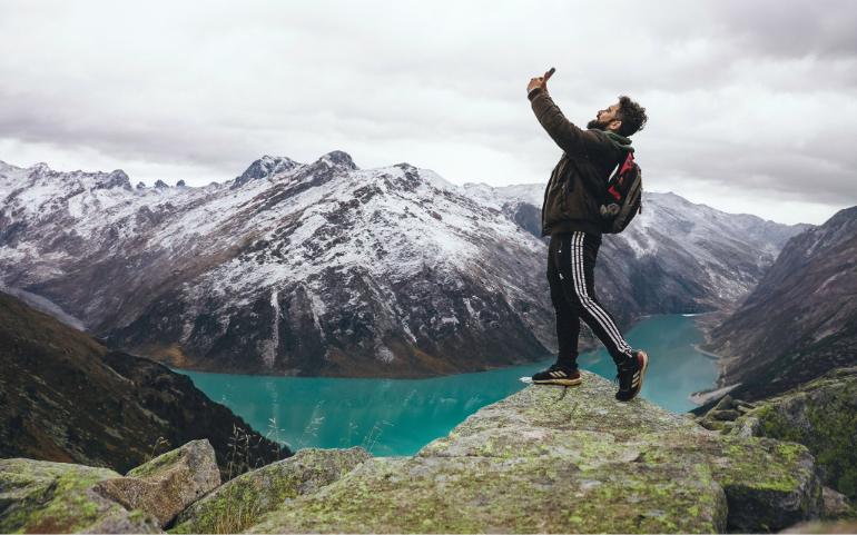 A man using a mobile at a breathtaking mountain.
