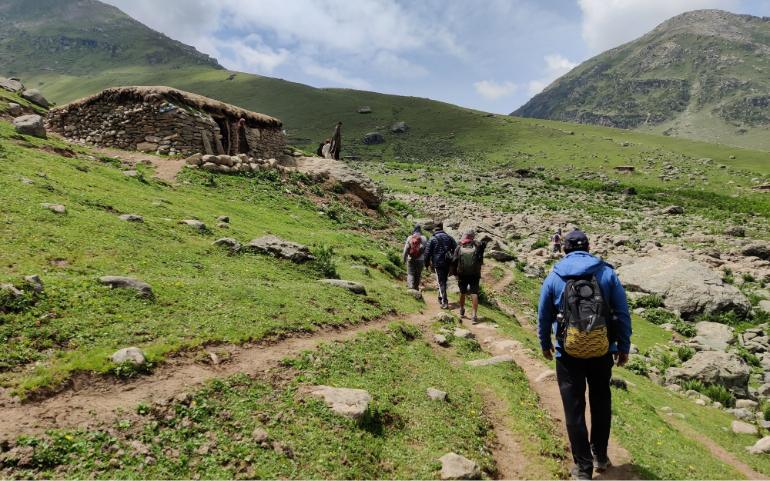 Hikers Walking Toward a Stone Hut in the Mountains