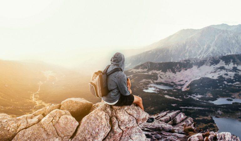 A lone traveler with a backpack sitting on a mountain rock
Rachel Claire/Pexels