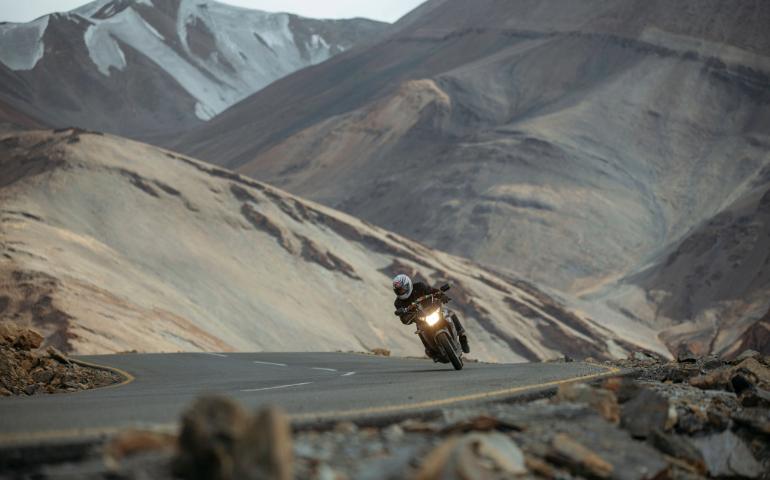 Motorcyclist navigating a winding road amid the stunning landscape of the Ladakh mountains.