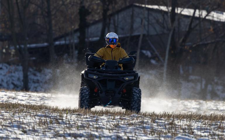 A Person on an ATV Rides Through a Snow-Covered Field During Winter
