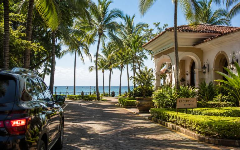 Palm-lined resort pathways opening towards the Arabian Sea, with a car arriving nearby.