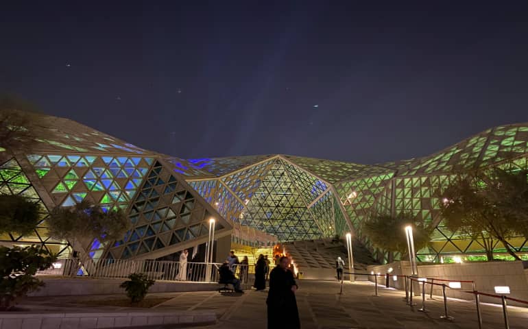 A group of people outside a building at night in Riyadh
