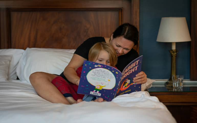 A mother reading story to his child in a hotel room