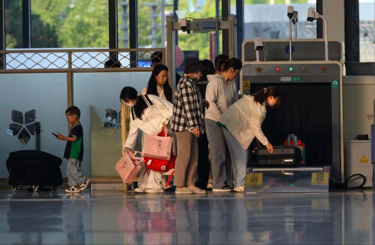 Travelers undergo security screening at an airport terminal.