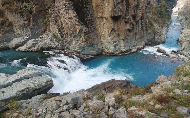 View of a blue river flowing through towering rocky cliffs in Aharbal 