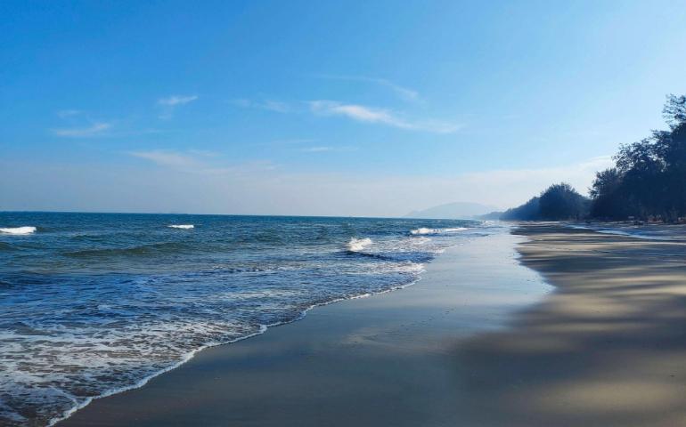 Tranquil beach scene at Hua Hin, Thailand with waves and clear blue sky.