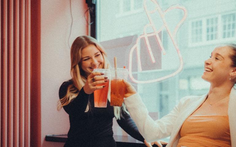 Two women happily toasting with drinks
