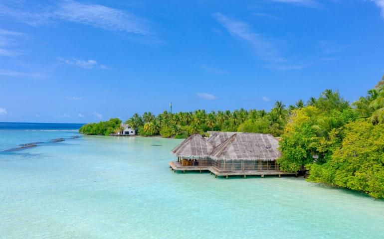 A tranquil overwater bungalow surrounded by azure waters and lush greenery in the Maldives.