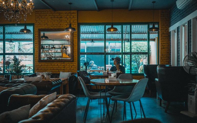 Relaxing café atmosphere with a man in a hat using the phone amidst chic interiors.