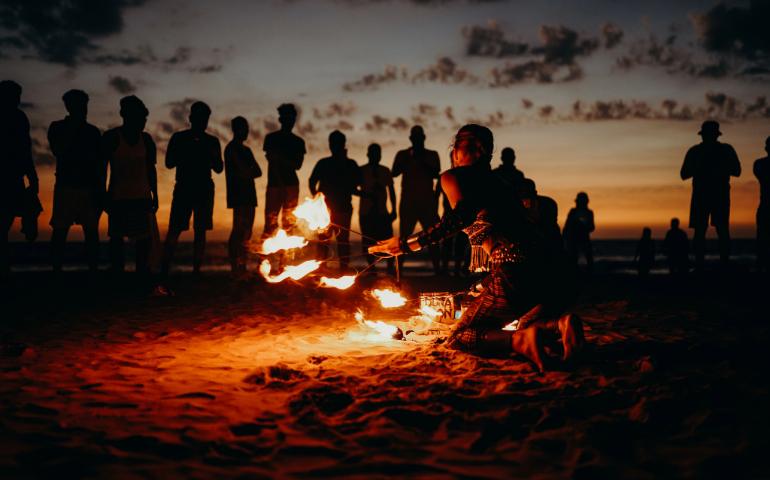 A mesmerizing fire performance on a beach at sunset with a captivated crowd in Goa.