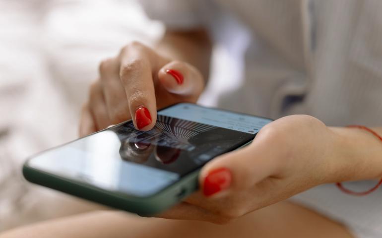 A person with red nails using a smartphone with a touch screen interface.