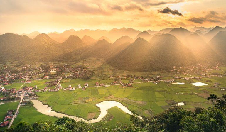 view of lush rice fields and limestone mountains at sunrise enveloped in golden light in Vietnam
Duc Nguyen/Pexels
