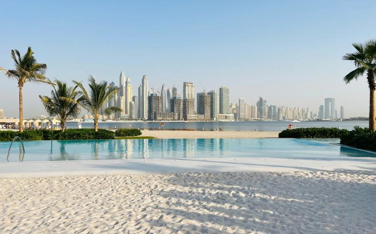 Luxurious beachfront pool overlooking the iconic Dubai skyline on a sunny day