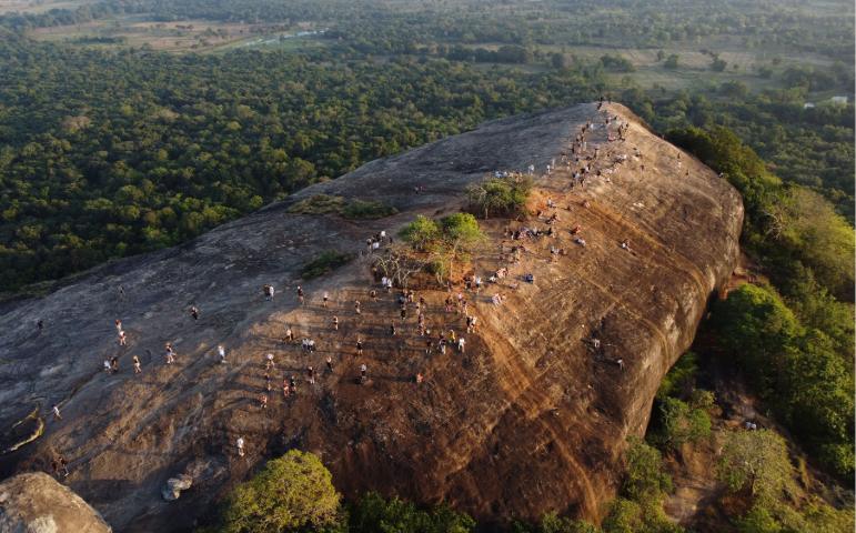 View of Pidurangala Rock with visitors enjoying the sunset in Sigiriya, Sri Lanka.