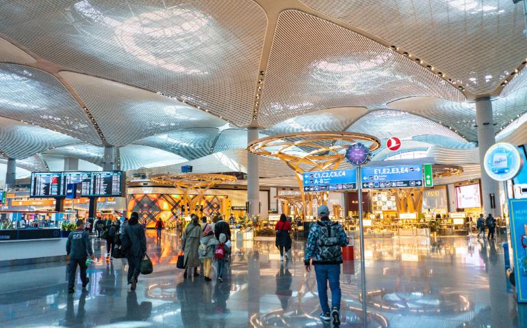 Spacious airport interior with travelers, shops, and architectural details.