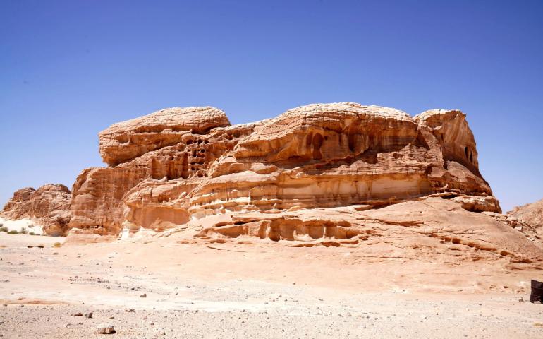 Vivid sandstone rock in a desert setting under a clear blue sky.