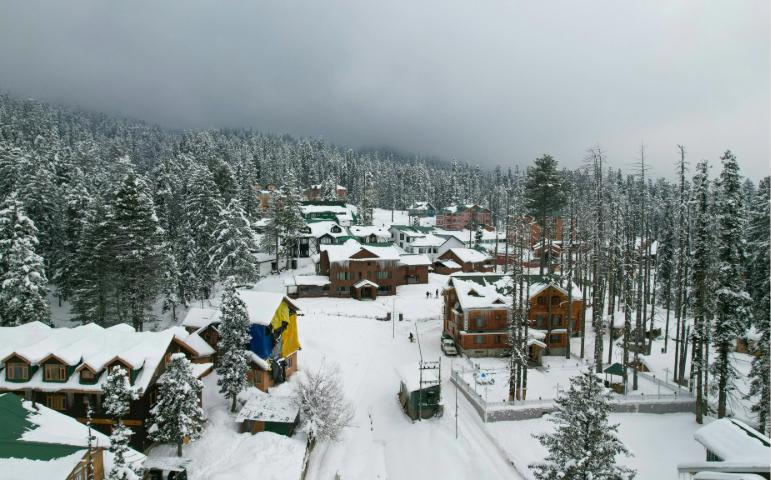 Winter Scene in Gulmarg Showing Snow-Covered Buildings and Coniferous Trees.