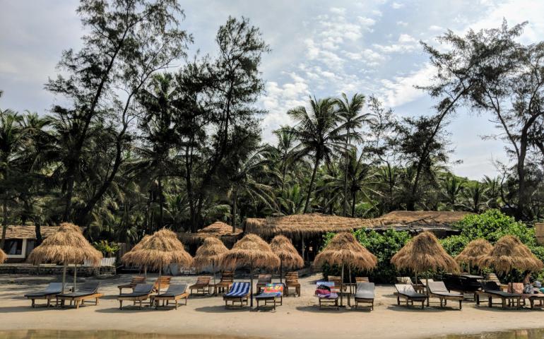 Beachside view with nipa huts and palm trees in Goa