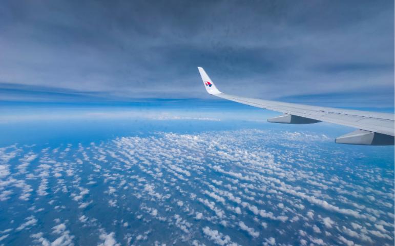 View of clouds from an airplane window showcasing wing and sky