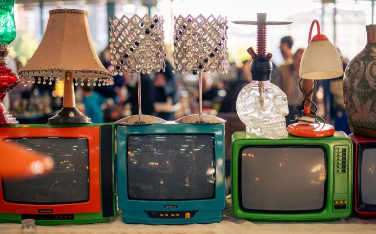 Colorful vintage TVs and decorative lamps on display at a vibrant flea market.
