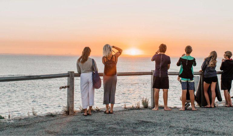 A group of people watching a beautiful sunset over the ocean.
Image Credit: Rachel Claire/Pexels