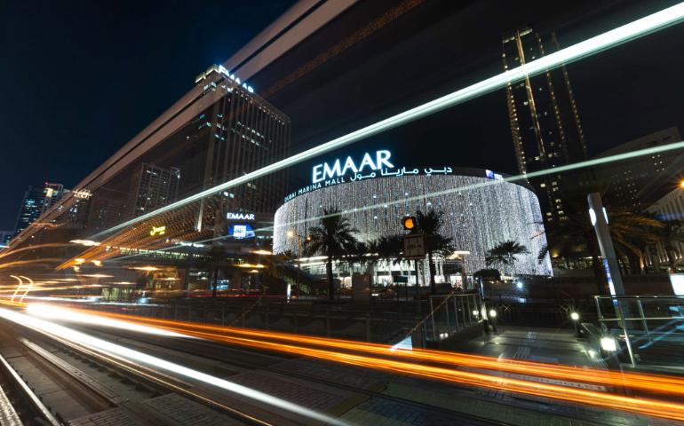 Night view of Dubai Marina Mall with dynamic light trails creating a vibrant urban scene.