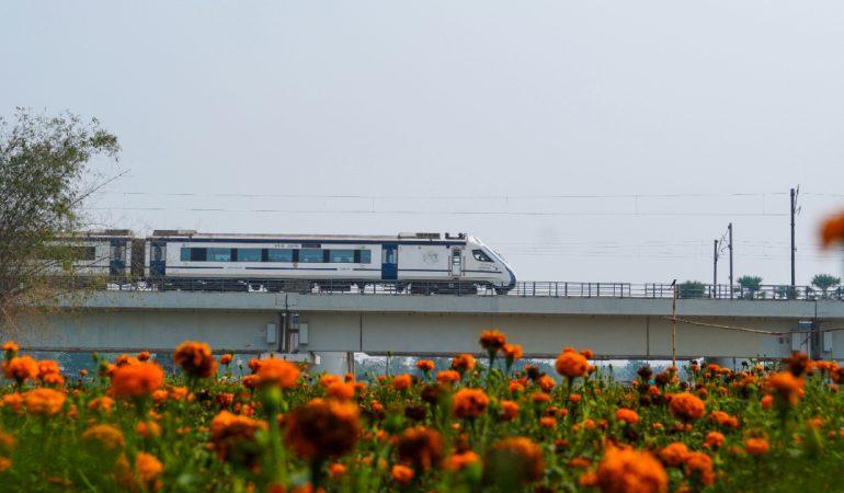 A sleek high-speed train travels across a raised bridge
