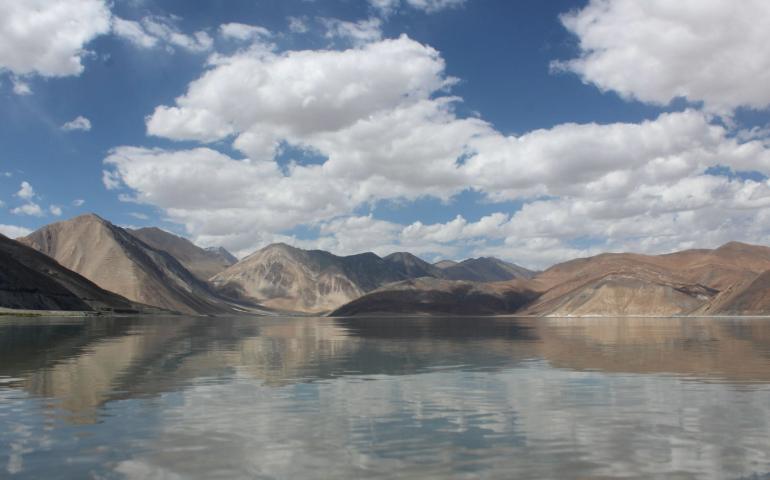 Lake in Ladakh reflecting a clear blue sky with clouds