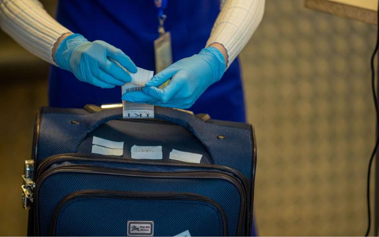 Close-up of airport security process with gloved hands inspecting luggage tags.
