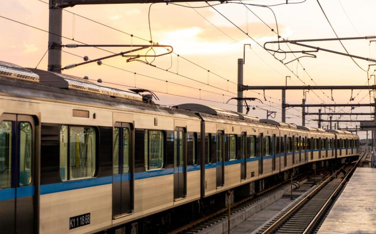 Train travels along tracks at sunset