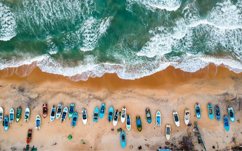 Shot of vibrant boats lined on sandy shores of Arugam Bay, Sri Lanka