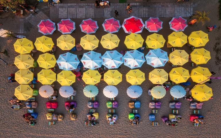 View of colorful beach umbrellas and seats on Bali's sandy shore